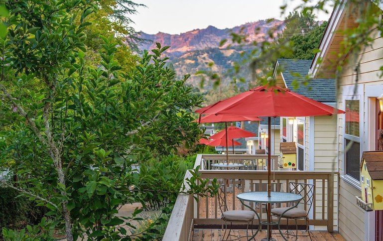 A side view of the cottages’ patios, which feature tables with bright red umbrellas where guests can enjoy a view of the mountains | Best Calistoga Hotels