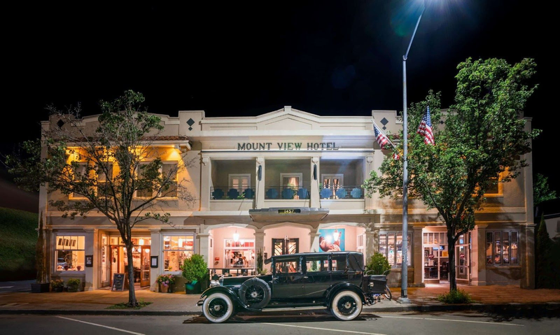 The large and ornate Mount View Hotel is pictured at night with an old fashioned car waiting out front | Best Calistoga Hotels