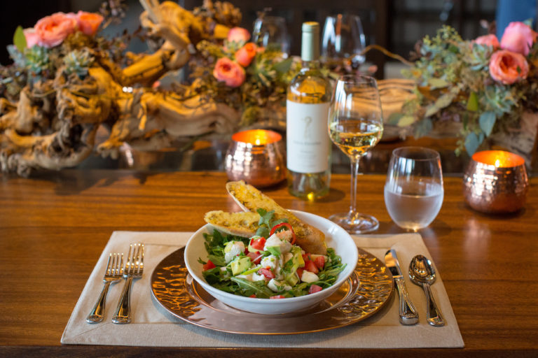 Gourmet salad with wine on elegant floral dinner table