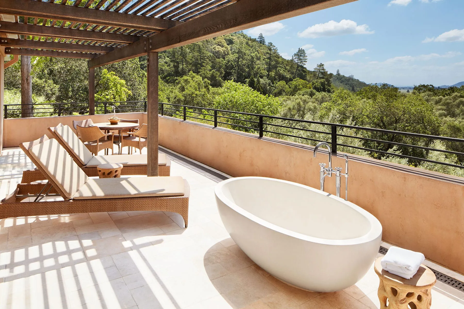 Outdoor tub and lounge area with lush forest view