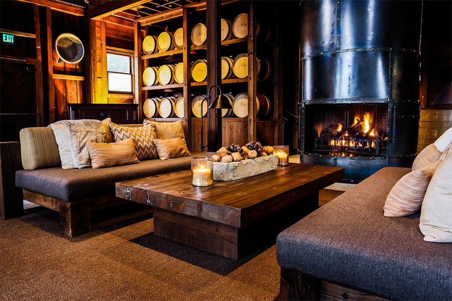 Cozy winery lounge with fireplace, wooden table, and barrels