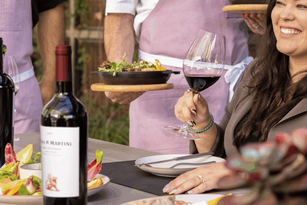 Woman enjoying red wine at outdoor lunch gathering