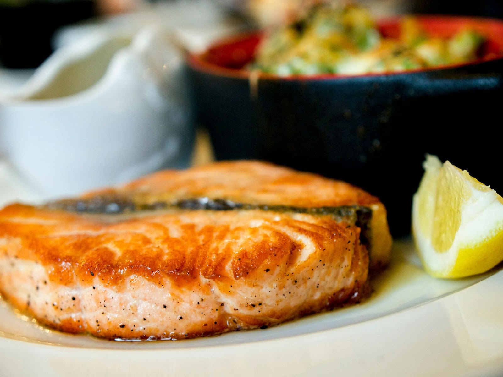 Seared salmon fillet served with lemon wedge and sides
