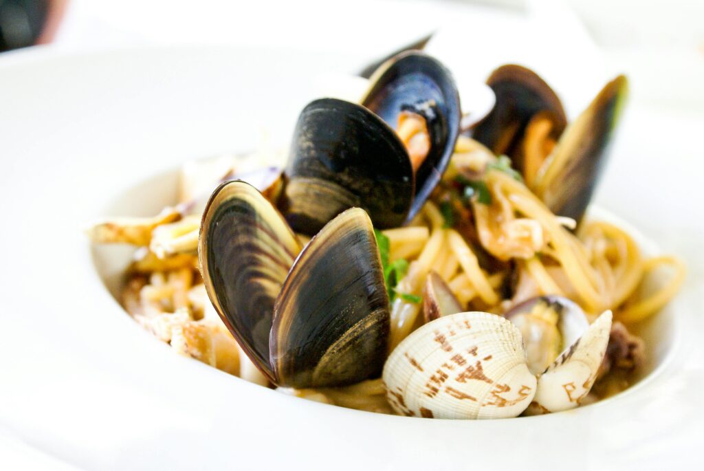 Seafood pasta with mussels and clams in white bowl