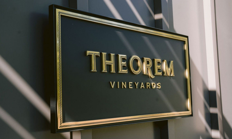 A black plaque reading “Theorem Vineyards” in gold lettering hangs on a wall | Best Wineries in Calistoga