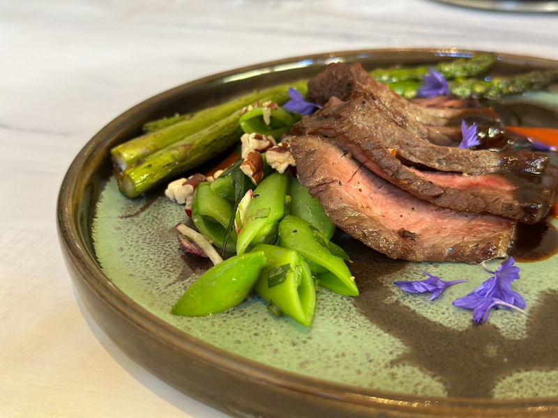 Sliced steak with asparagus, snap peas, and edible flowers