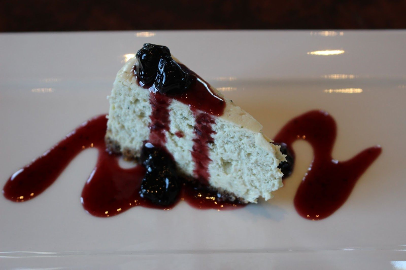 Cheesecake slice topped with berry sauce and compote