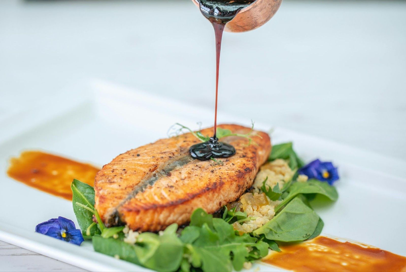 Grilled salmon with sauce and greens on plate