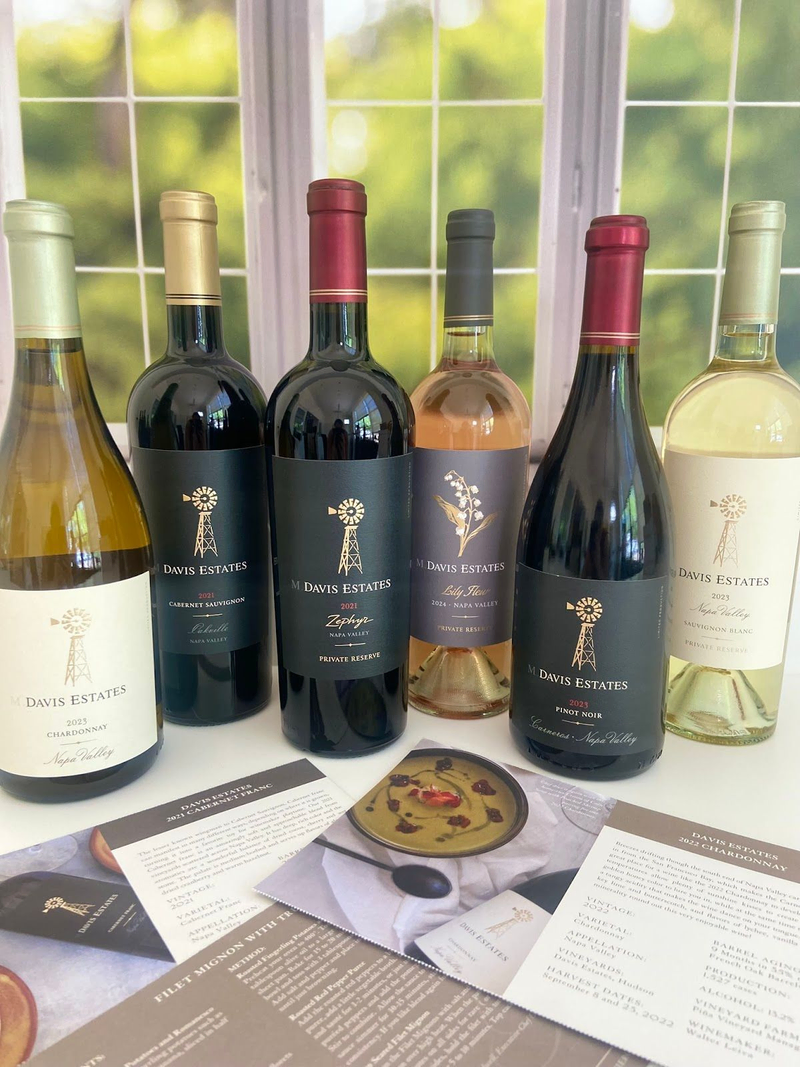 Davis Estates wine bottles lineup on table by window