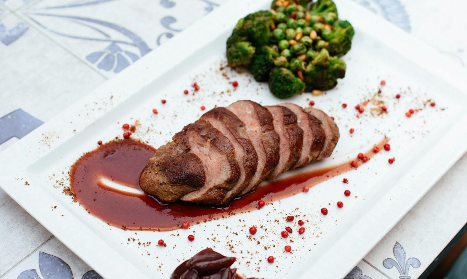 Sliced seared duck breast with sauce and broccoli