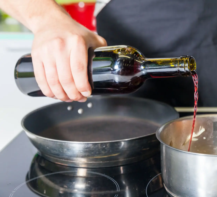 Pouring red wine into cooking pan